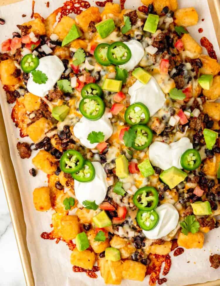 Tater tot nachos topped with jalapeno slices, avocado, sour cream and diced tomato.