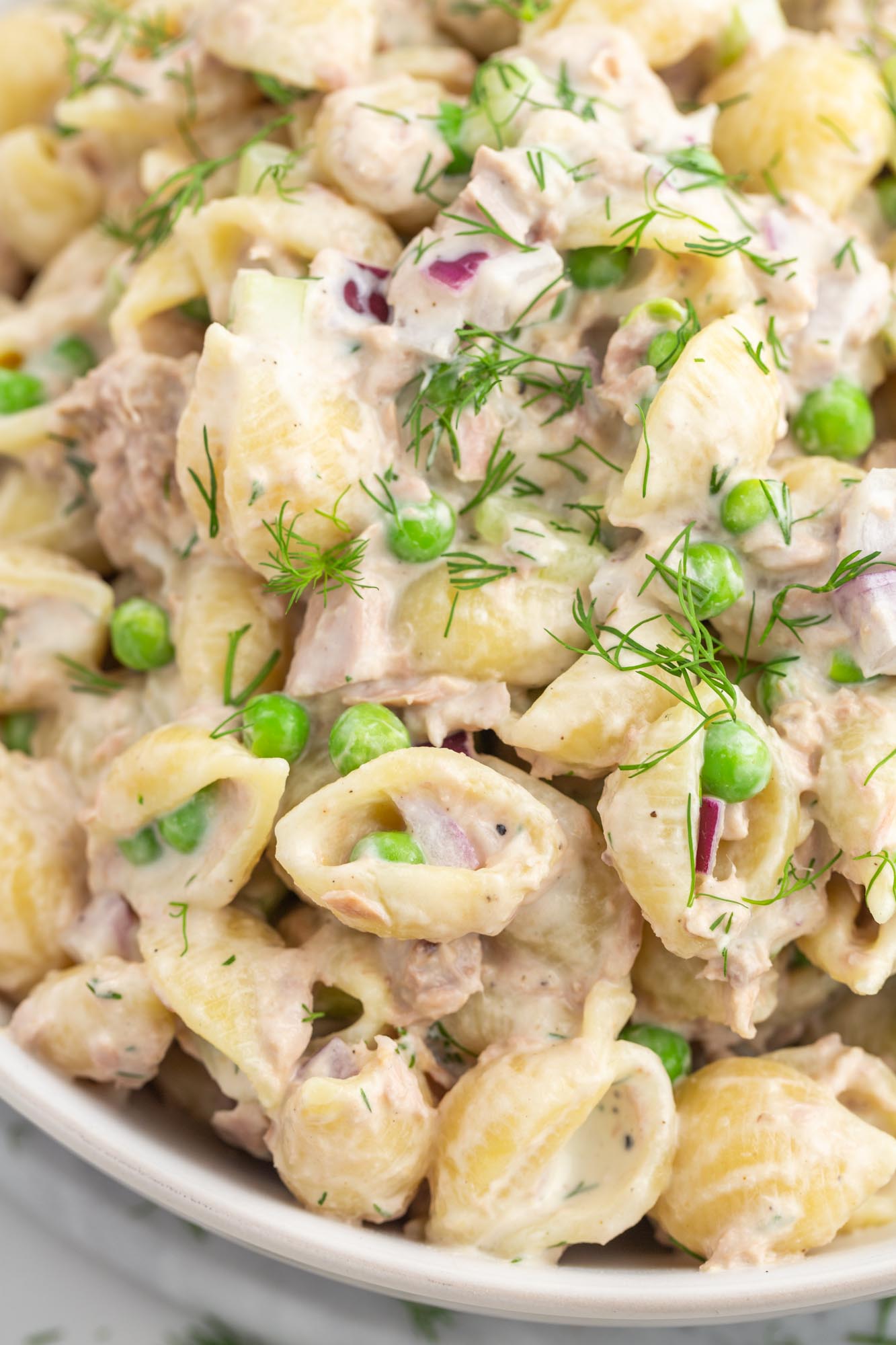 Tuna pasta salad with peas and dill, shown up close to show detail. 