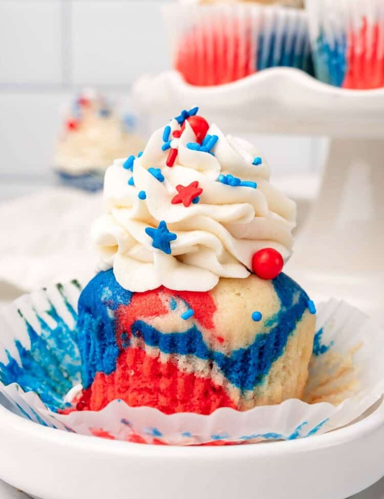 a red white and blue tie dye cupcake, unwrapped, on a small plate.