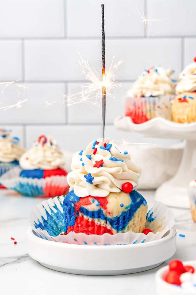 a red white and blue swirled cupcake with a lit sparkler on top