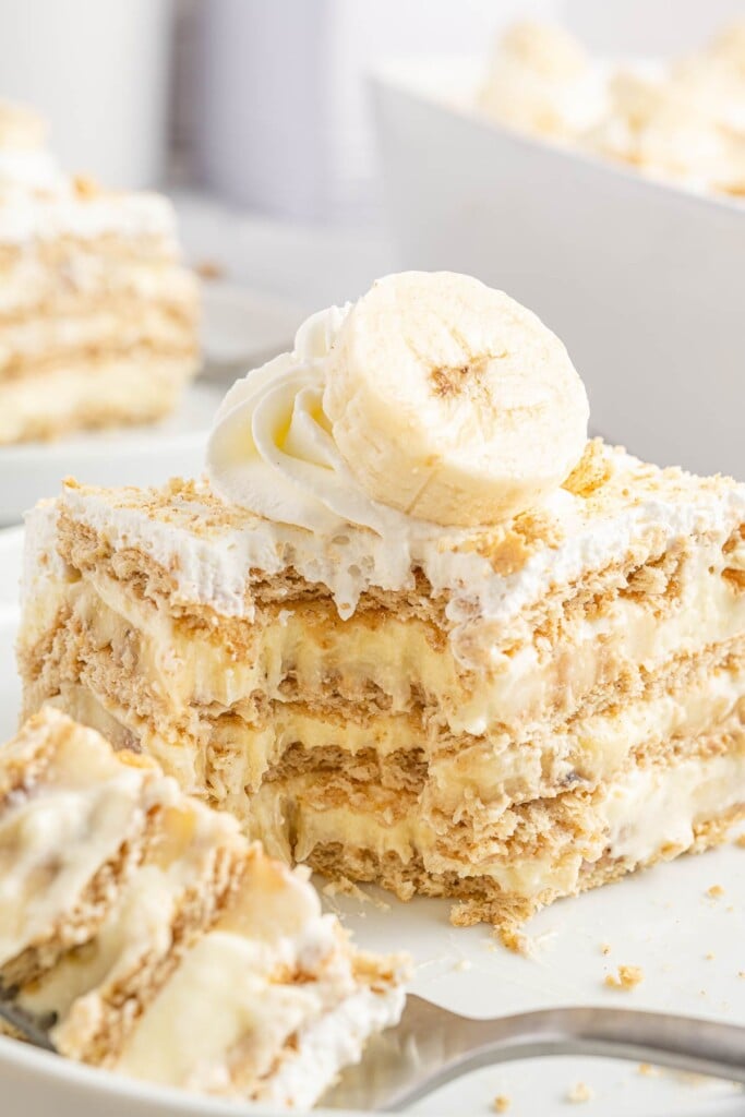 a square piece of graham cracker and banana pudding icebox cake with a bite taken off one corner