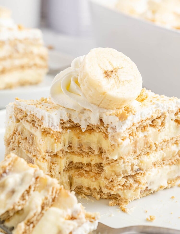 a square piece of graham cracker and banana pudding icebox cake with a bite taken off one corner
