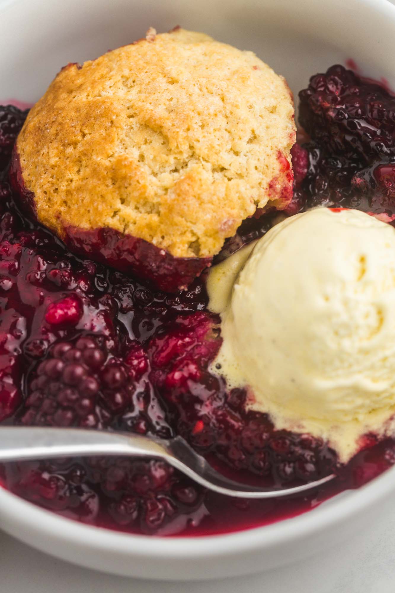 a bowl of blackberry cobbler with a scoop of vanilla ice cream on top