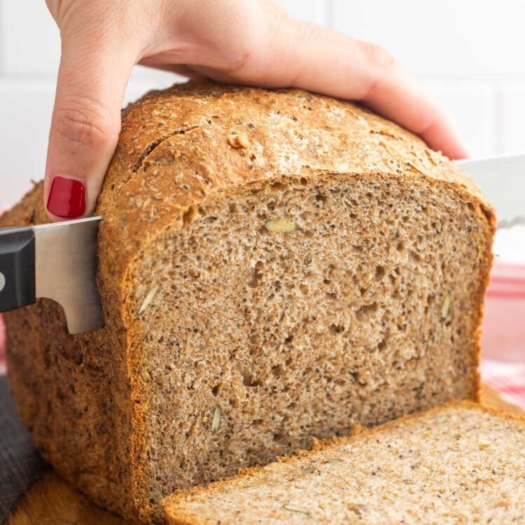 Cutting through a loaf of whole wheat seed bread made in the bread machine