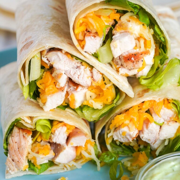 4 homemade grilled chicken cool wraps poiled on a plate with a side of avocado ranch.