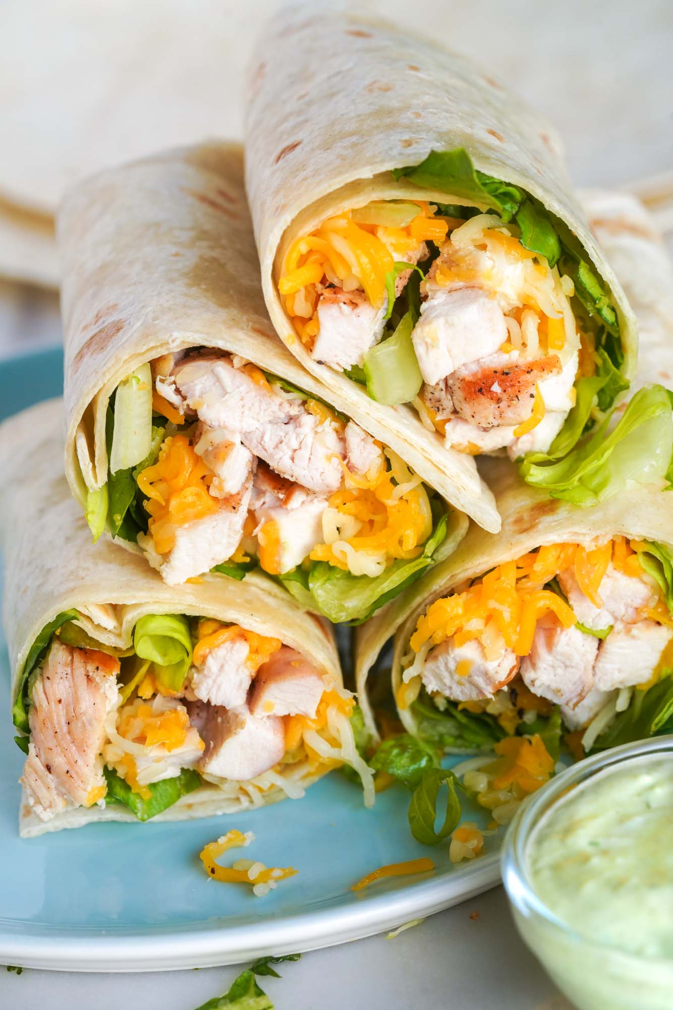 4 homemade grilled chicken cool wraps poiled on a plate with a side of avocado ranch.