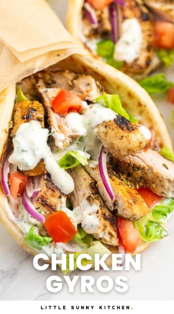 Close up shot of a chicken gyros wrap with extra tzatziki sauce, placed on a white marble surface, and overlay text that says "Chicken Gyros"
