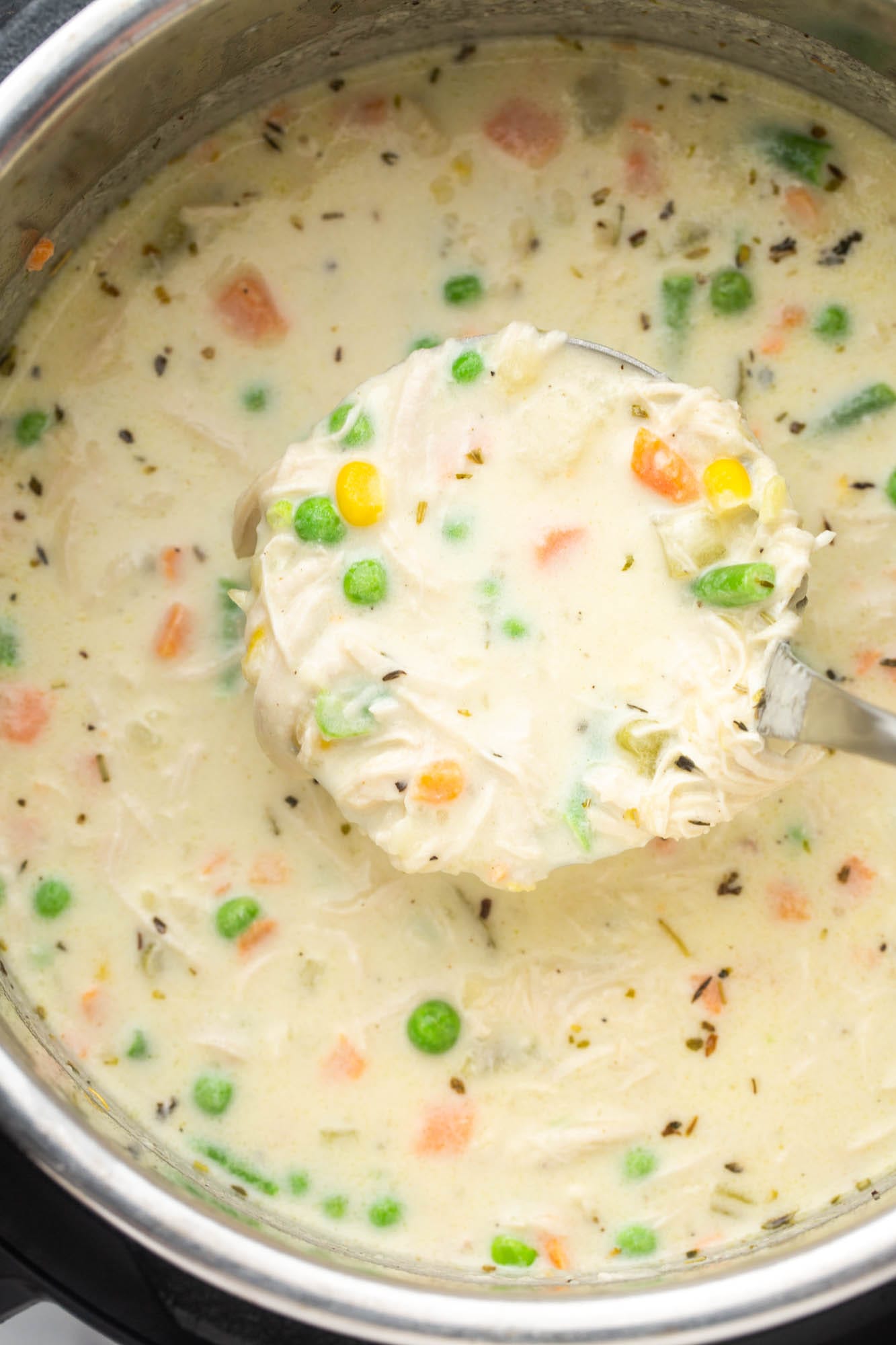 Creamy chicken pot pie soup with a ladle in the instant pot