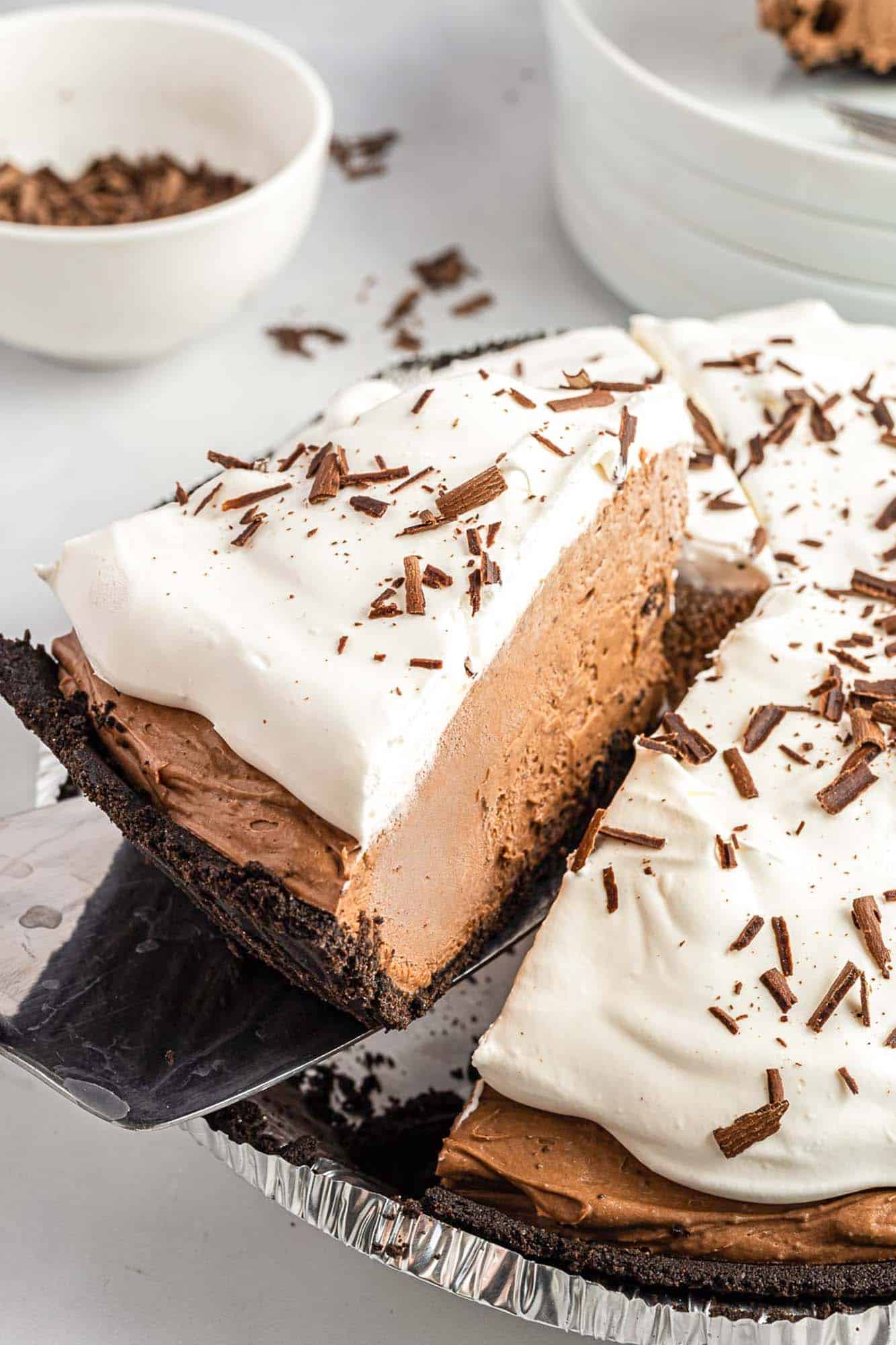 chocolate jello pudding pie with whipped topping. a slice is lifted up by a cake server