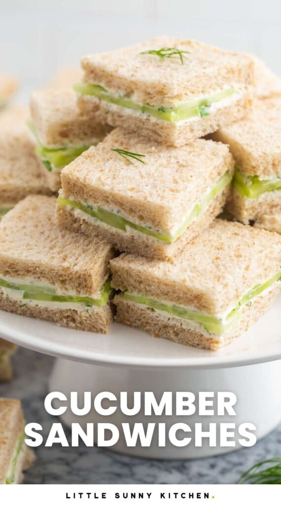 a stack of square cucumber sandwiches on wheat bread, filling a cake pedestal. Text at bottom of image says Cucumber Sandwiches