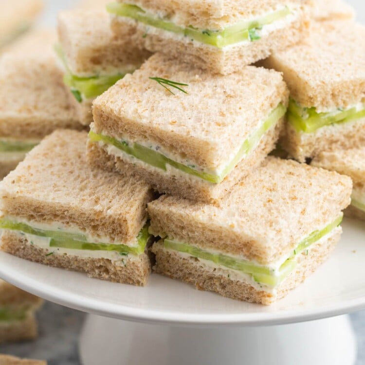 a cake pedestal filled with cucumber sandwiches