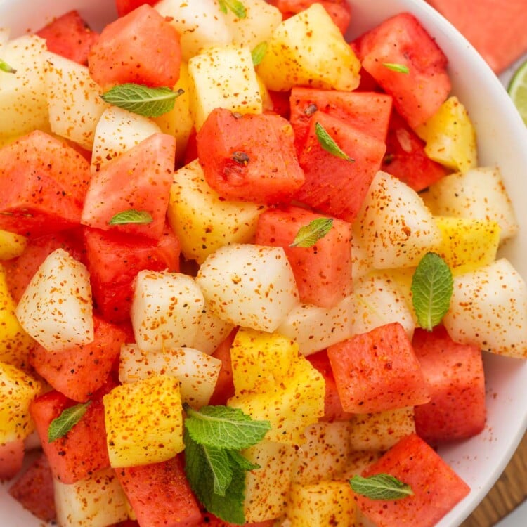 Overhead shot of a large bowl of mexican fruit salad, with mint and tajin.