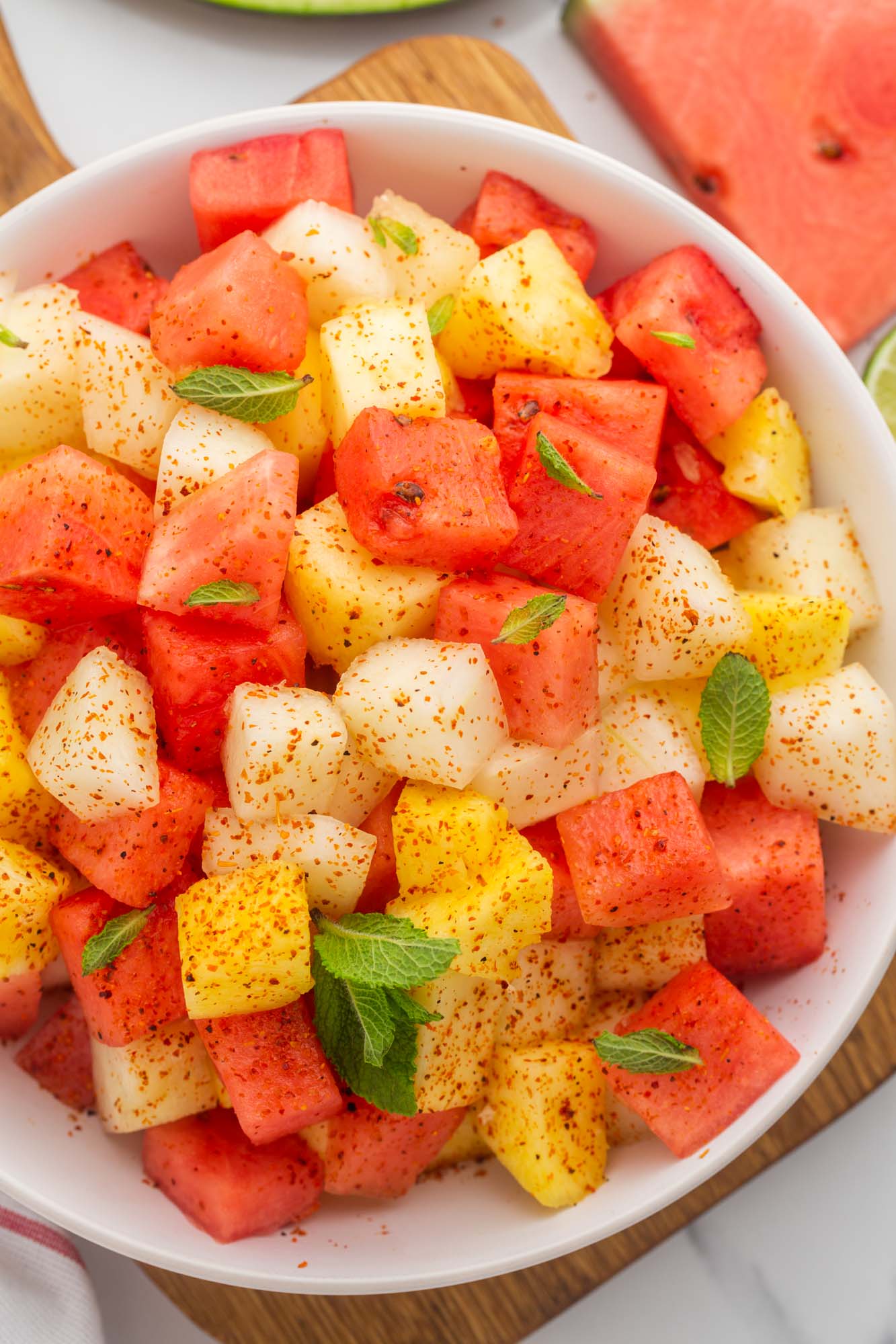 Overhead shot of a large bowl of mexican fruit salad, with mint and tajin.