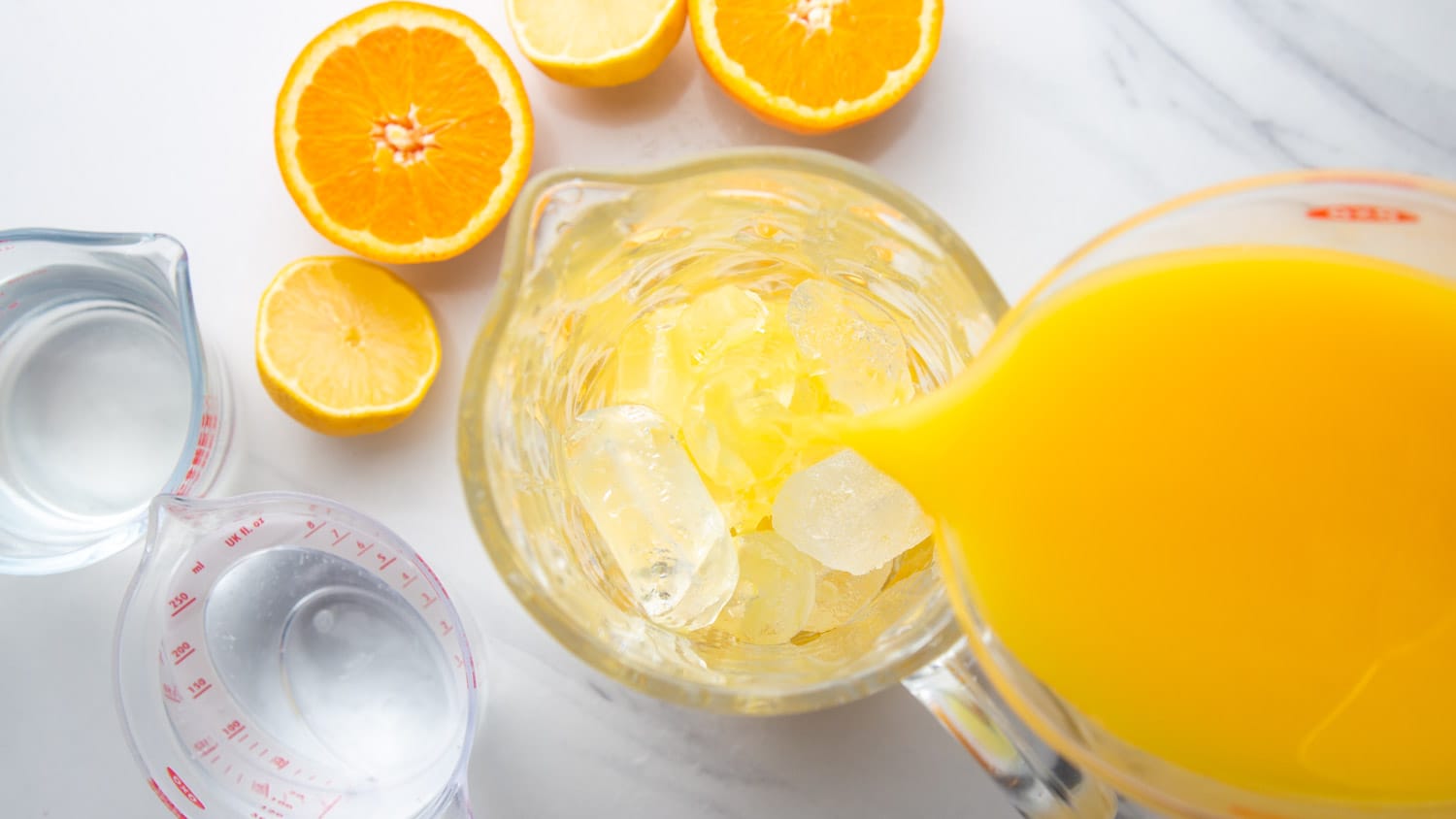 Pouring orange juice into a pitcher filled with ice.