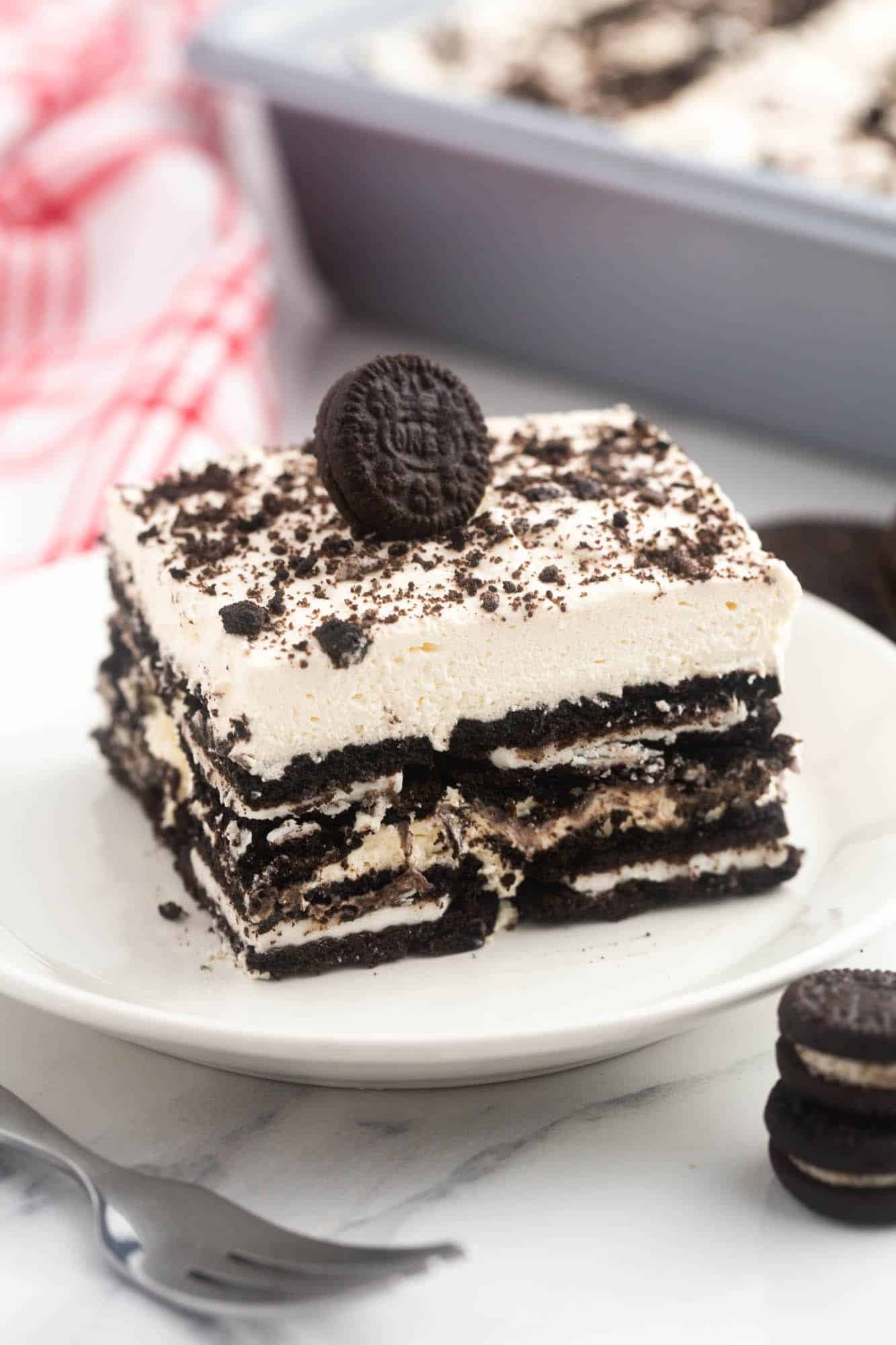 a square piece of layered oreo icebox cake with a miniature oreo on top. 