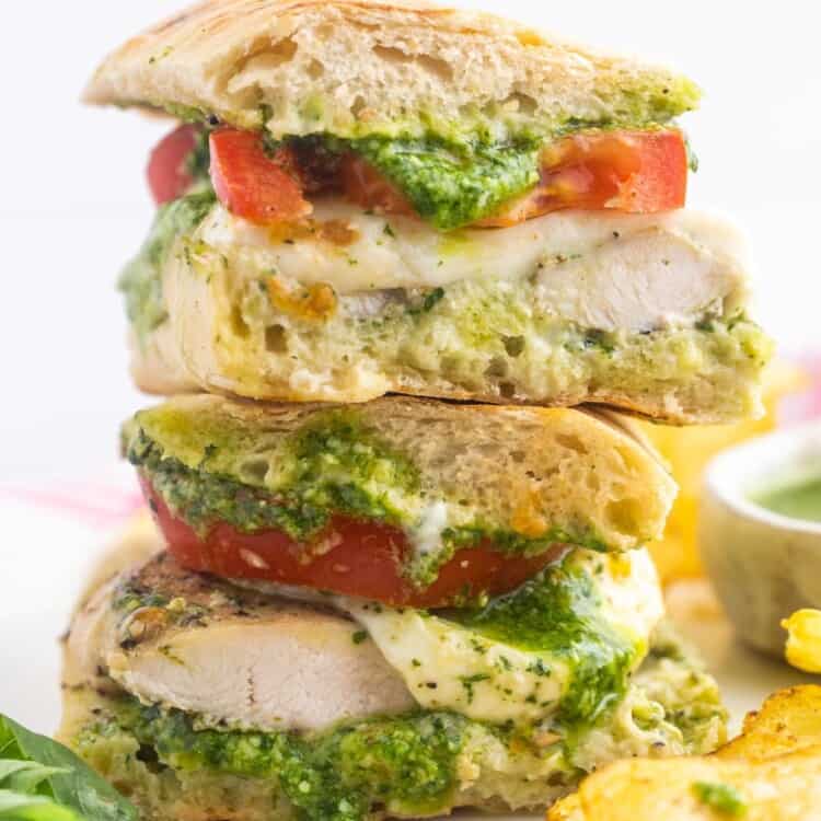a chicken sandwich on ciabatta bread cut in half and stacked on a plate.