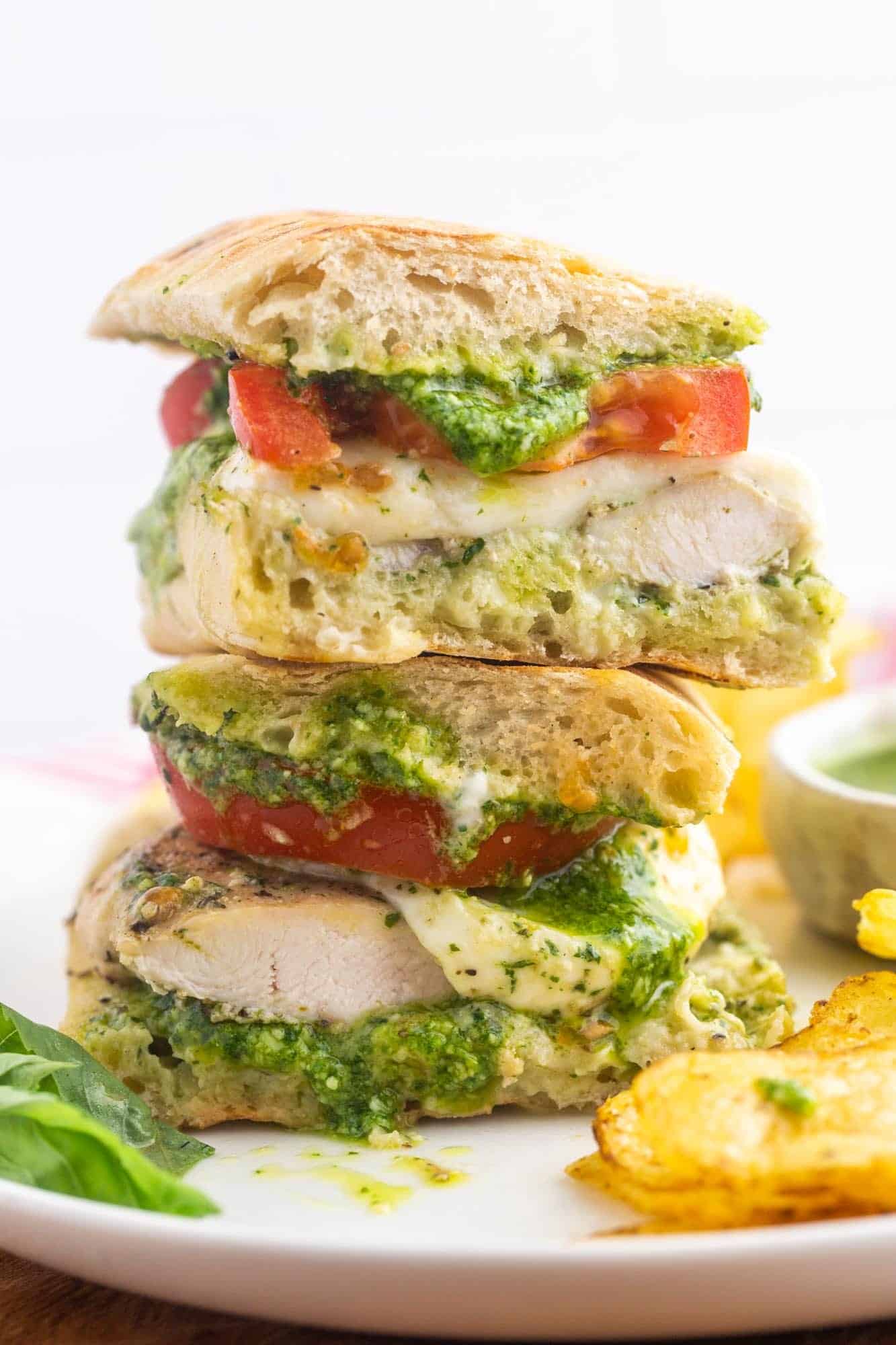 a chicken sandwich on ciabatta bread cut in half and stacked on a plate.