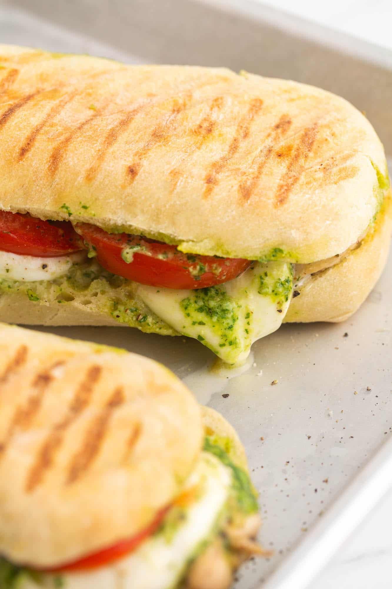 two sandwiches with tomatoes and pesto after being pressed in a panini maker