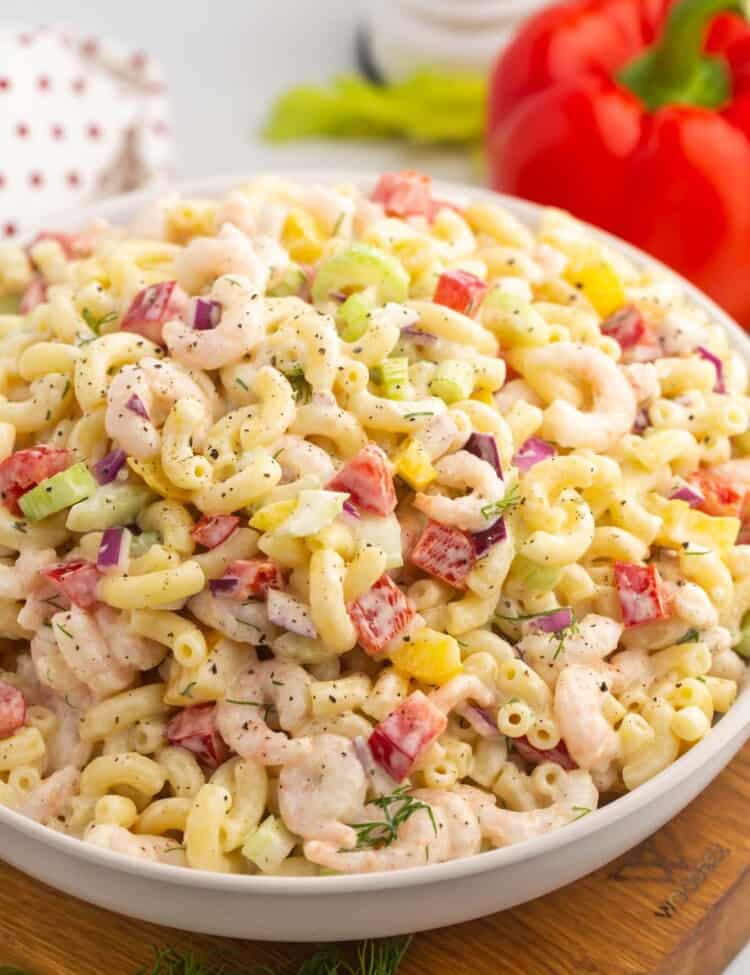a large white bowl filled with shrimp macaroni salad with diced bell peppers
