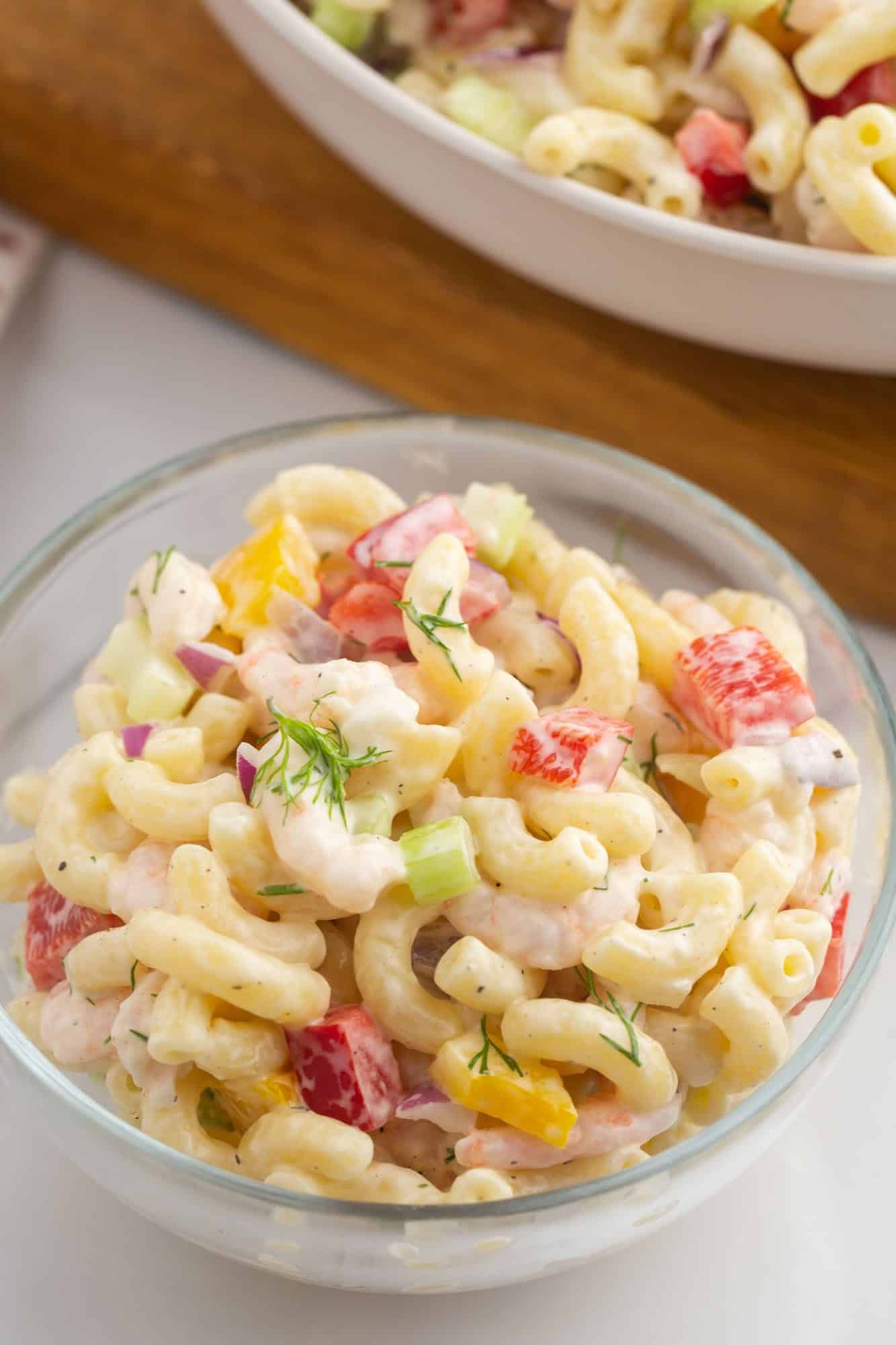 a small glass bowl of shrimp pasta salad with dill and bell peppers