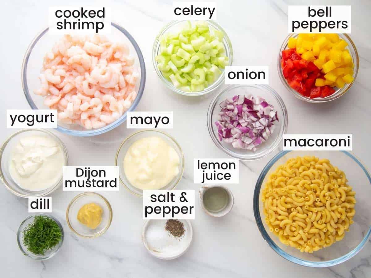 All of the ingredients needed for shrimp pasta salad, measured into separate bowls on a counter, viewed from overhead