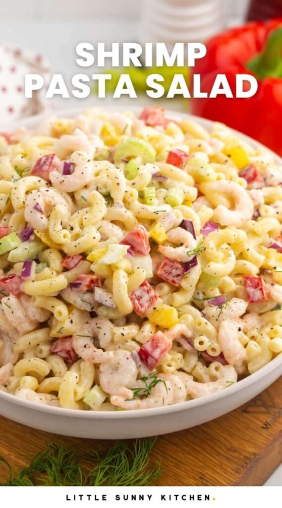 a large bowl of shrimp pasta salad on the table. White text at the top of the image says Shrimp Pasta Salad in capital letters