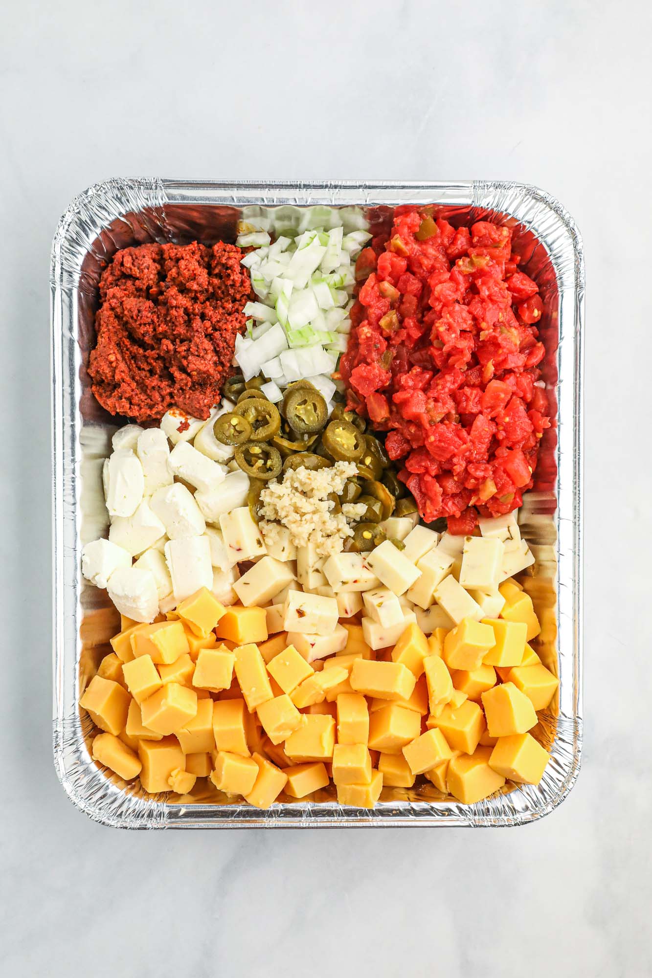 Overhead shot of queso ingredients in a foil Aluminum Pan
