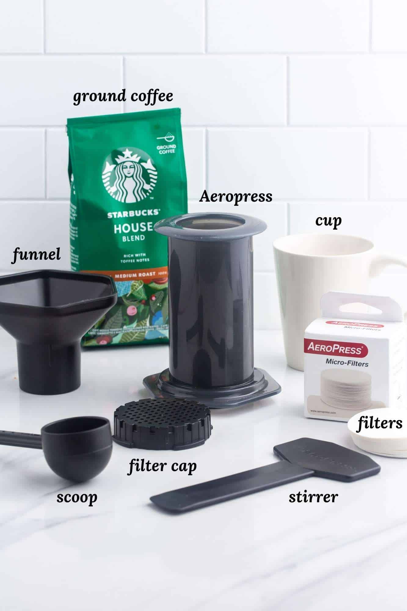 what you need to make aeropress coffee, including the brewer, parts, and accessories, a bag of starbucks coffee and a coffee cup