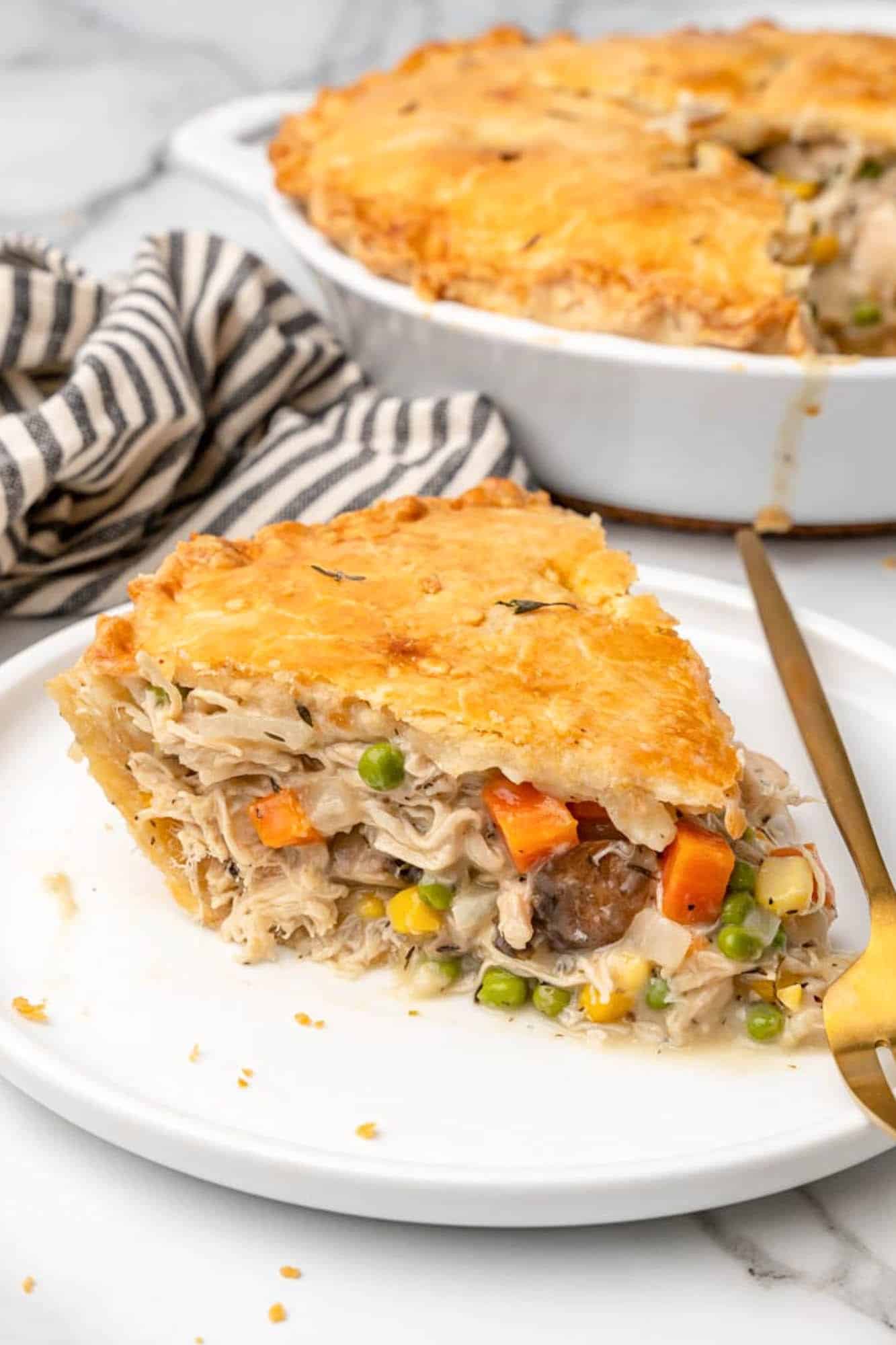 a wedge shaped slice of homemade chicken pot pie on a plate.