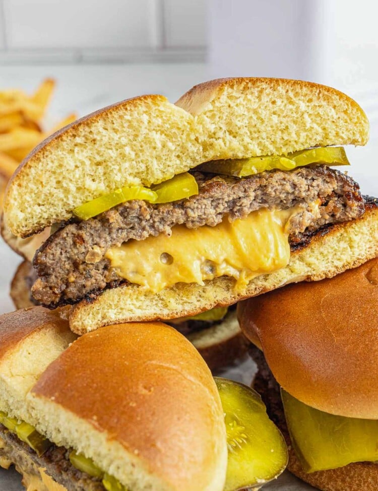 a juicy lucy hamburger on a bun stuffed with melty american cheese, sliced in half to show the texture.