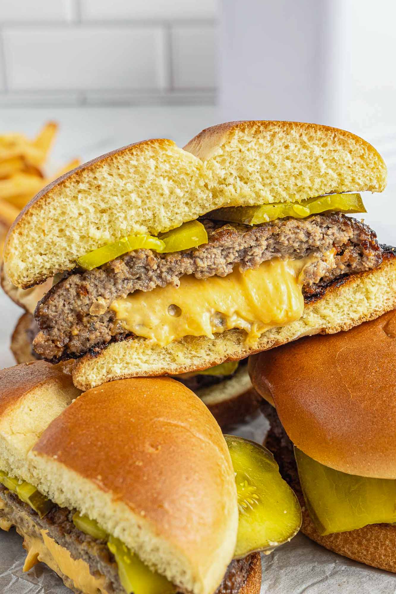 a juicy lucy hamburger on a bun stuffed with melty american cheese, sliced in half to show the texture.