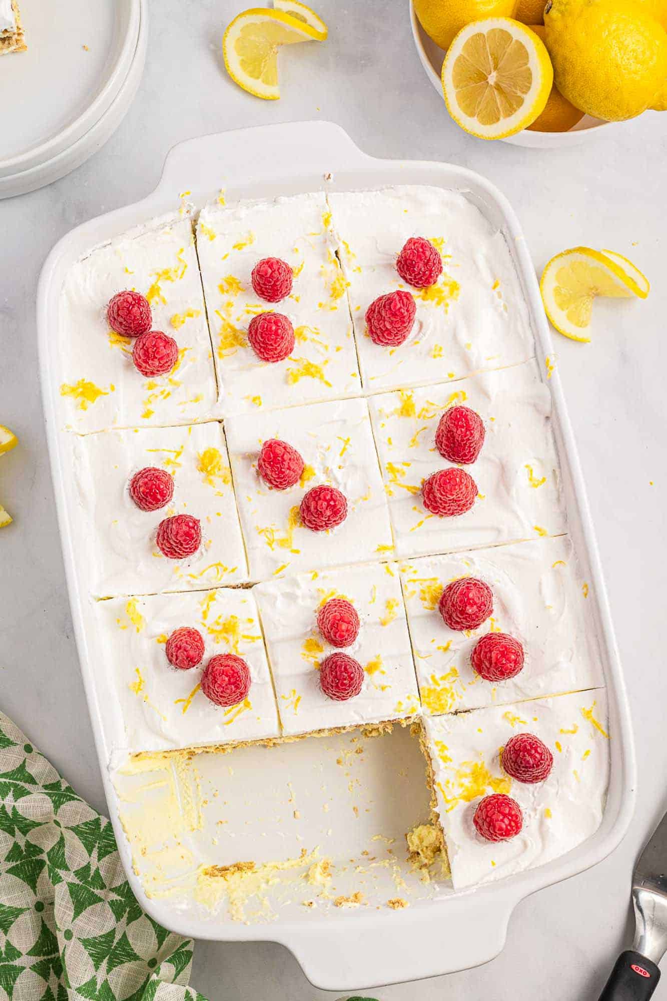 Overhead shot lemon icebox cake, garnished with fresh raspberries and lemon zest.