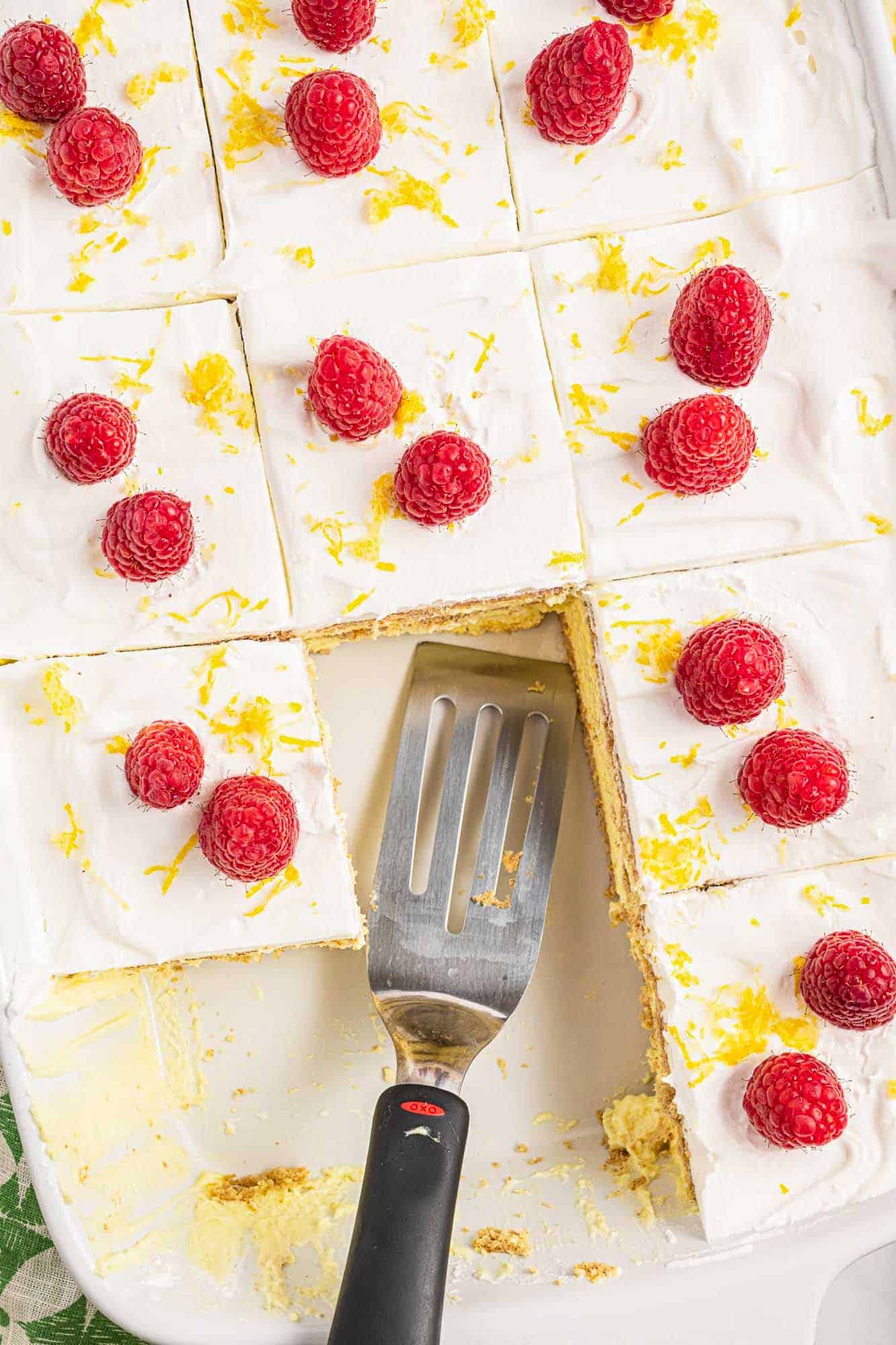 Overhead shot lemon icebox cake, garnished with fresh raspberries and lemon zest.