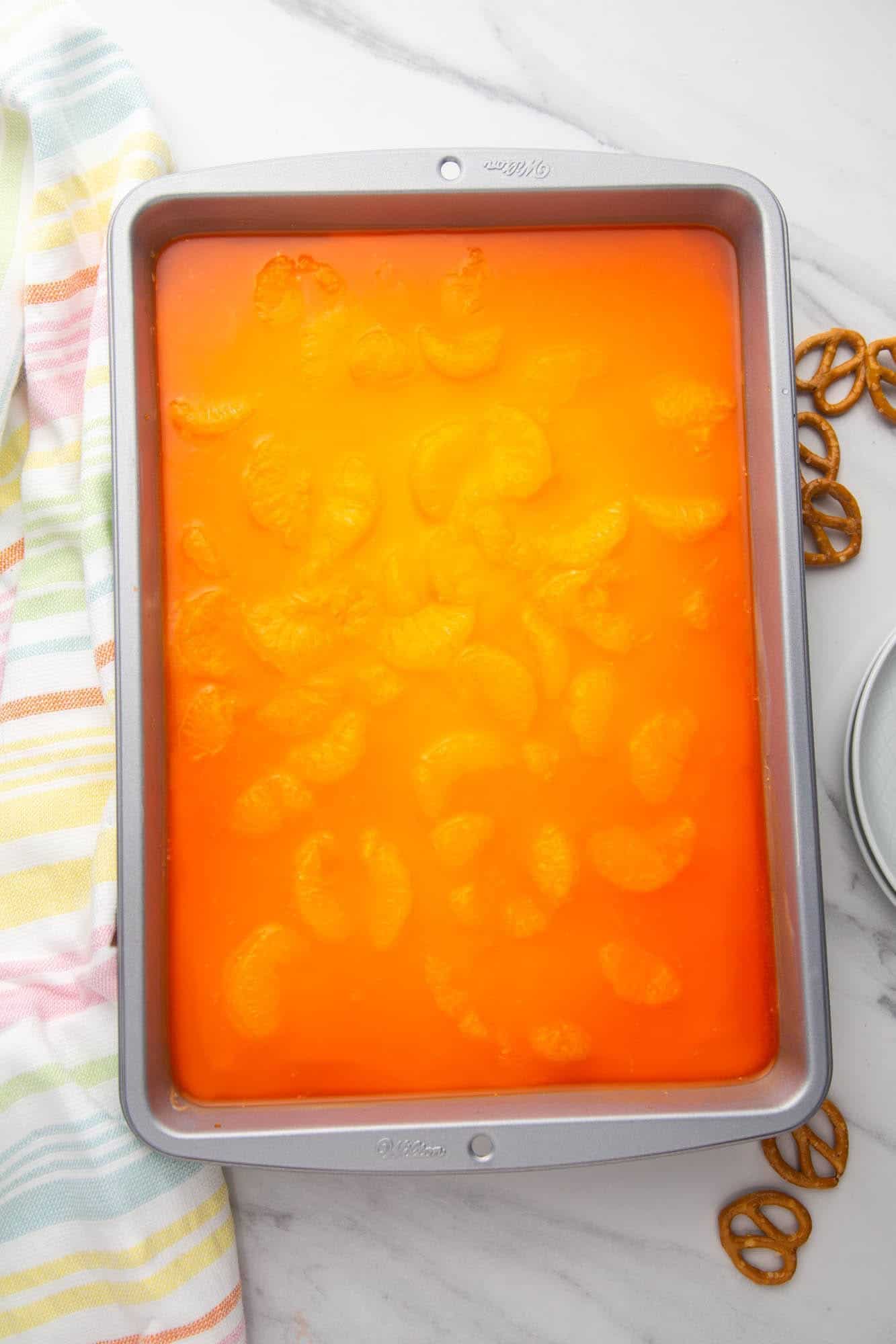a pan of pretzel salad with orange jello, viewed from above