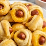 Pigs in a blanket stacked on a white plate