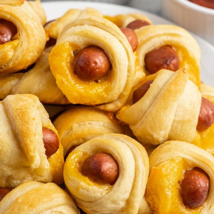 Pigs in a blanket stacked on a white plate