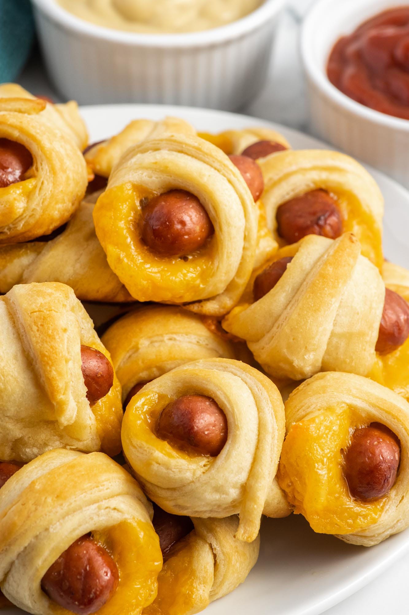 Pigs in a blanket stacked on a white plate