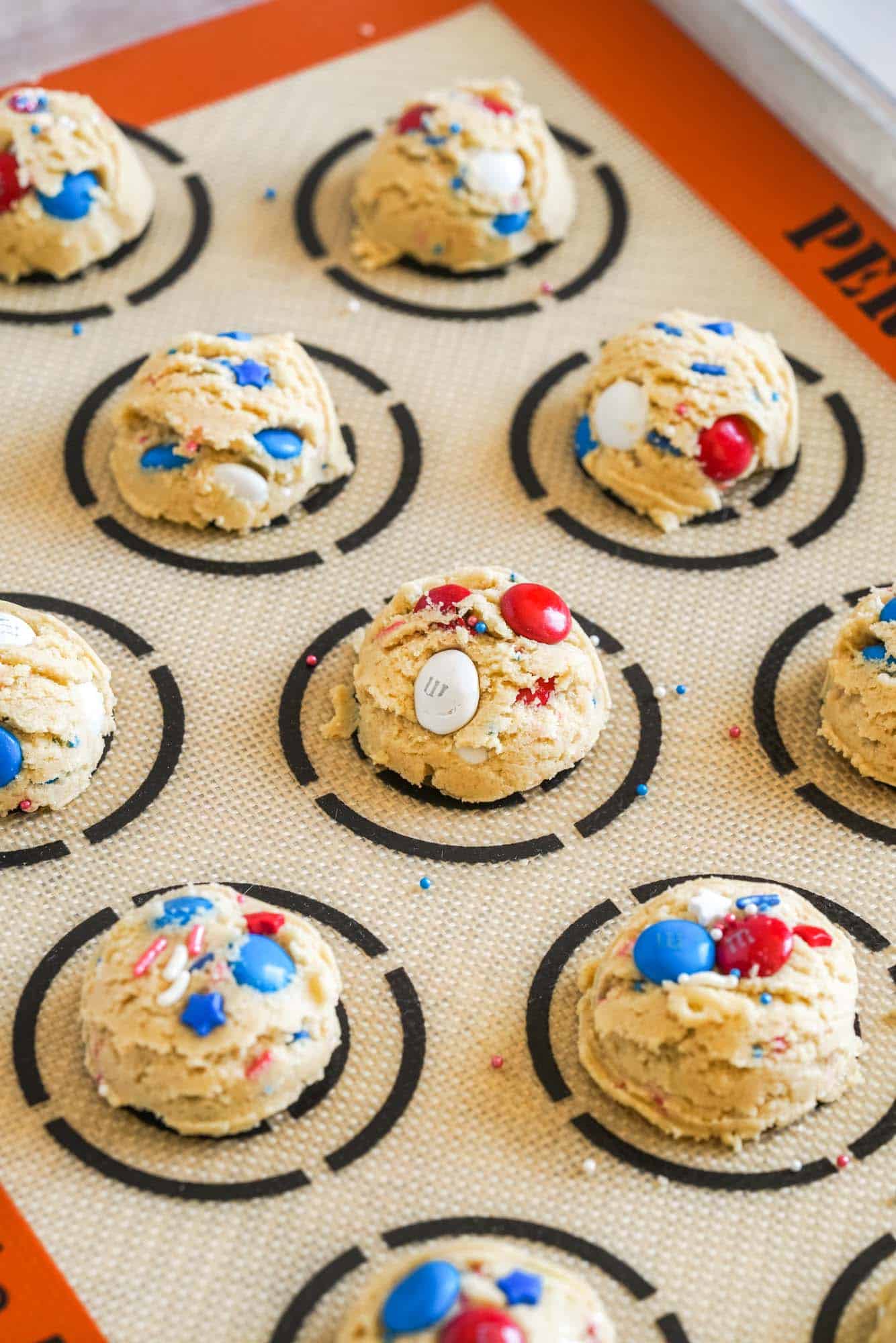 M&M cookie dough balls on a silpat cookie mat