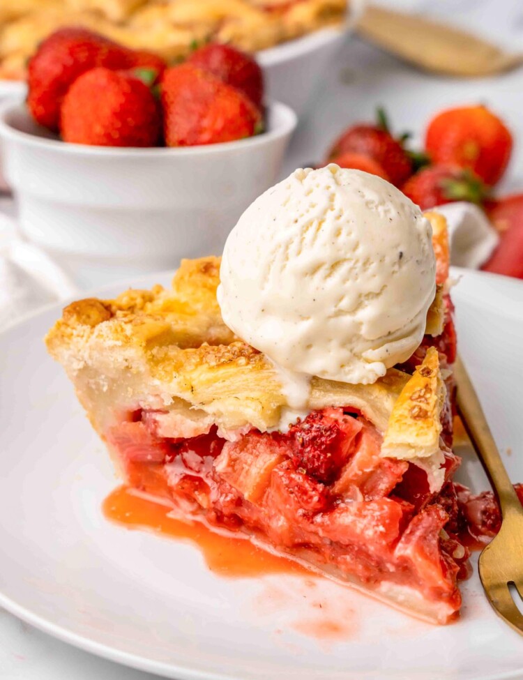 A slice of strawberry rhubarb pie with a scoop of ice cream on top