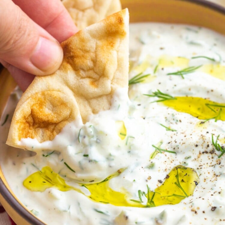 Dipping a piece of pita bread in tzatziki sauce