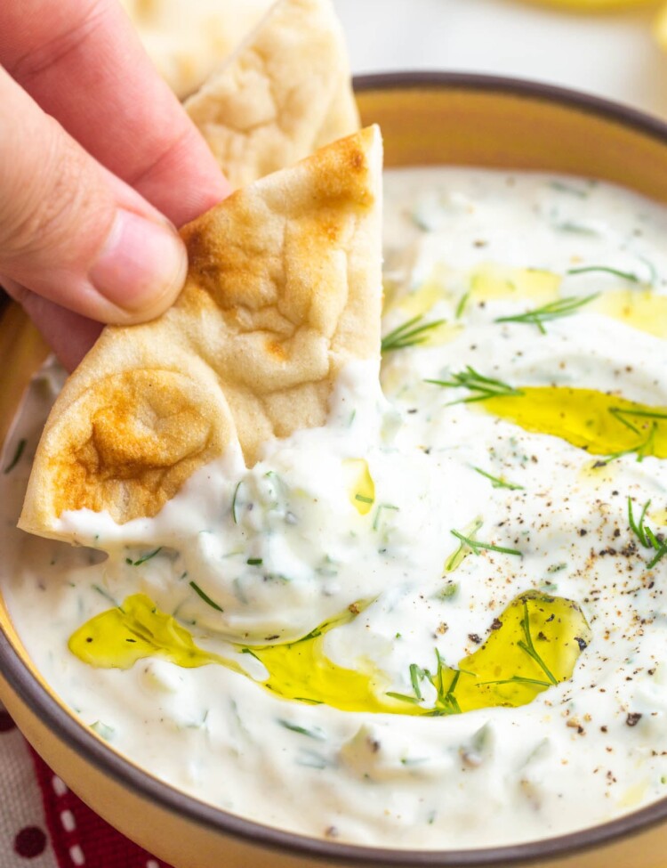 Dipping a piece of pita bread in tzatziki sauce