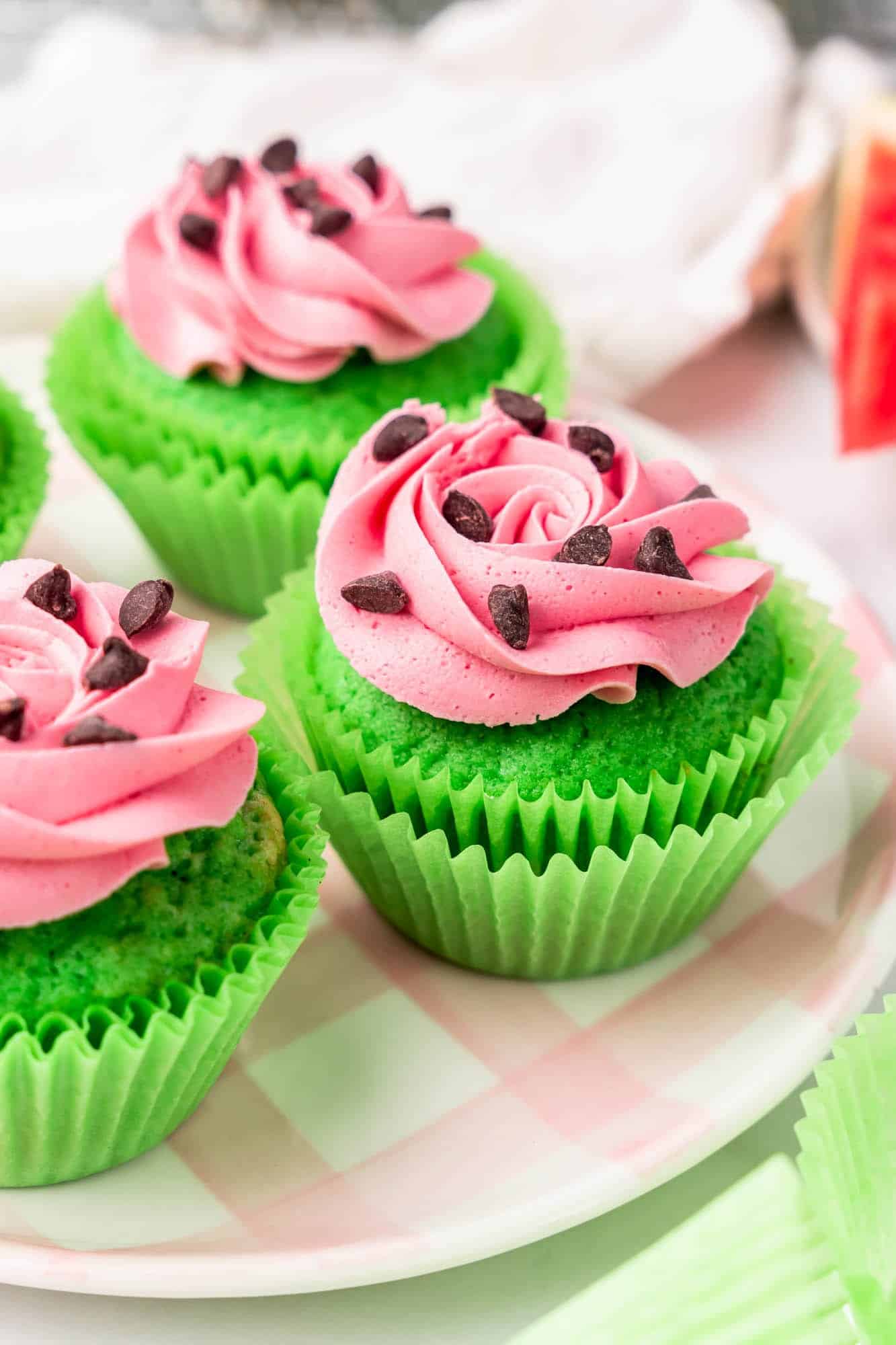 green cupcakes in green cupcake liners, topped with pink frosting and chocolate chips to resemble watermelon