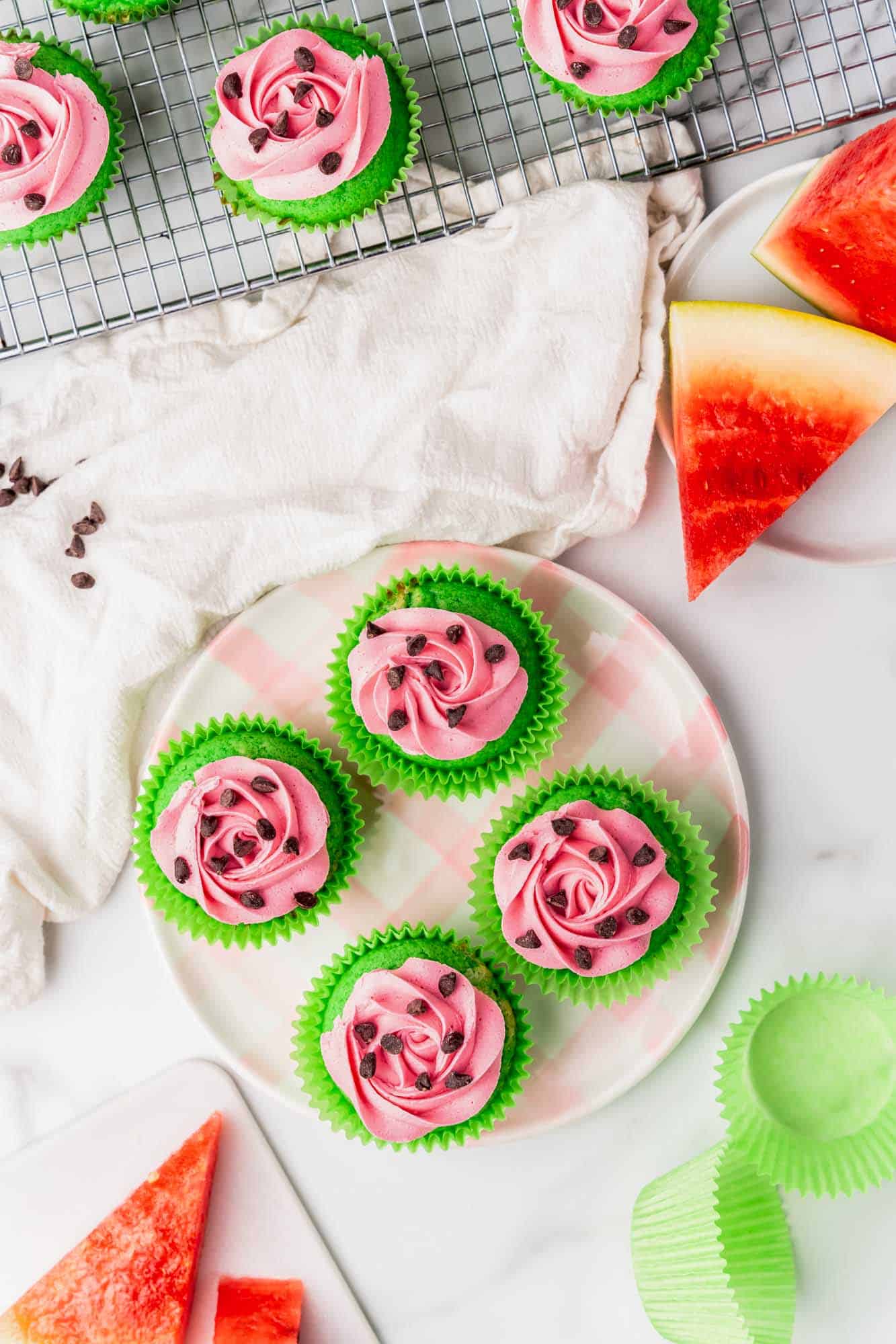 a plate of pink and green watermelon cupcakes, viewed from above. 