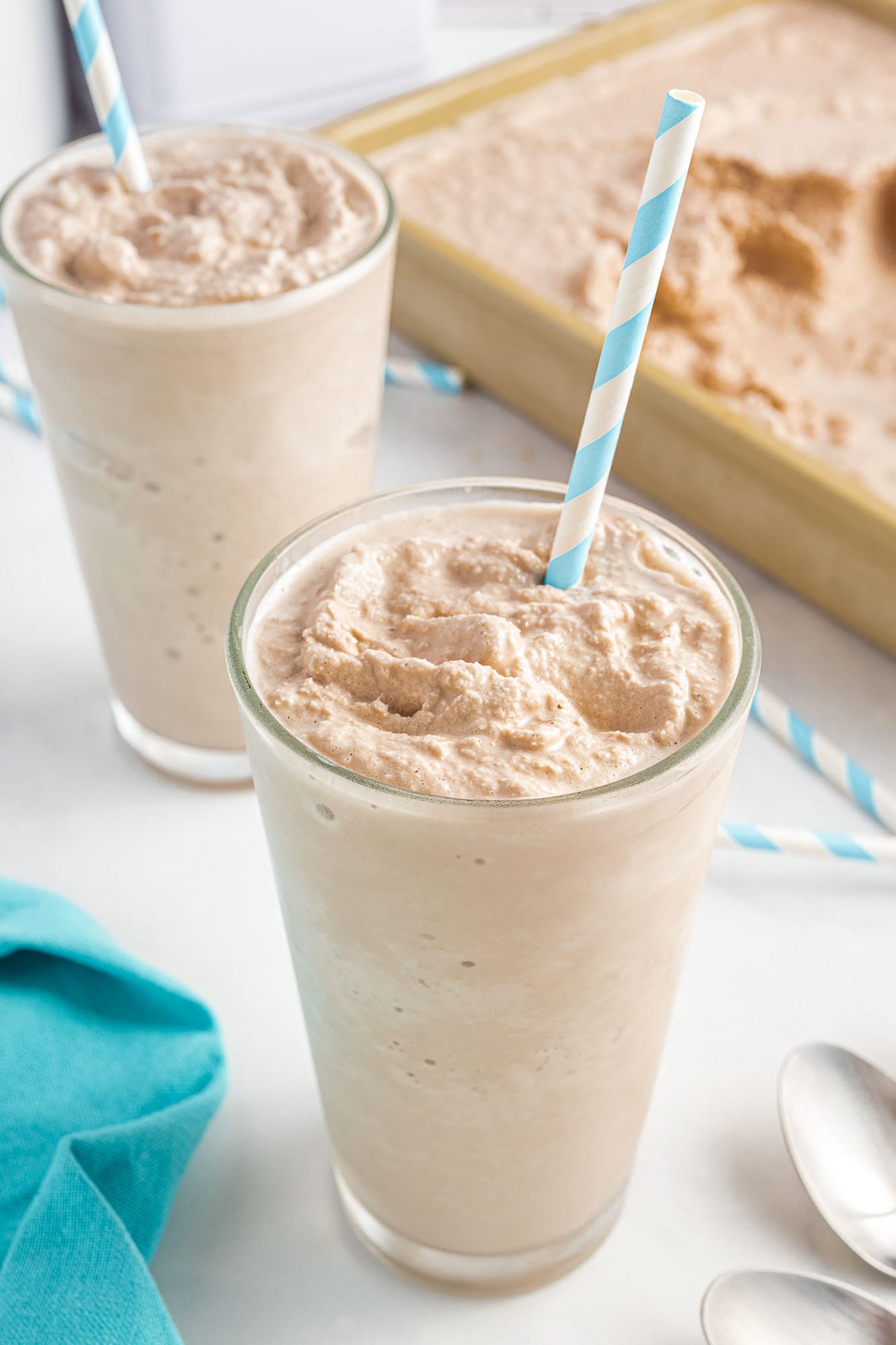 two glasses of chocolate wendy's frosty with paper straws