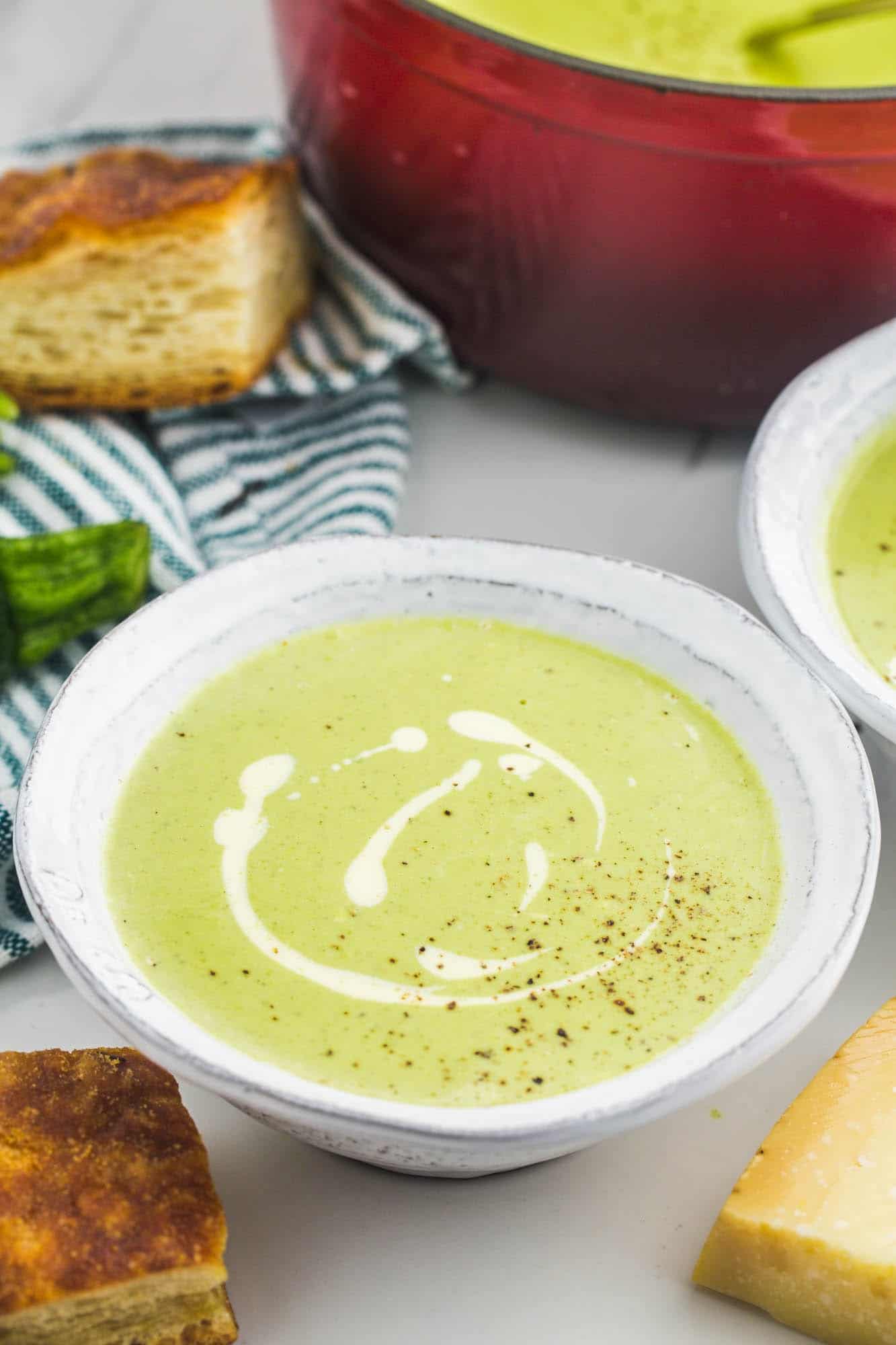 a bowl of creamy zucchini soup garnished with cream and pepper
