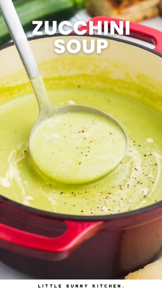a ladle serving creamy, green zucchini soup from a red dutch oven.
