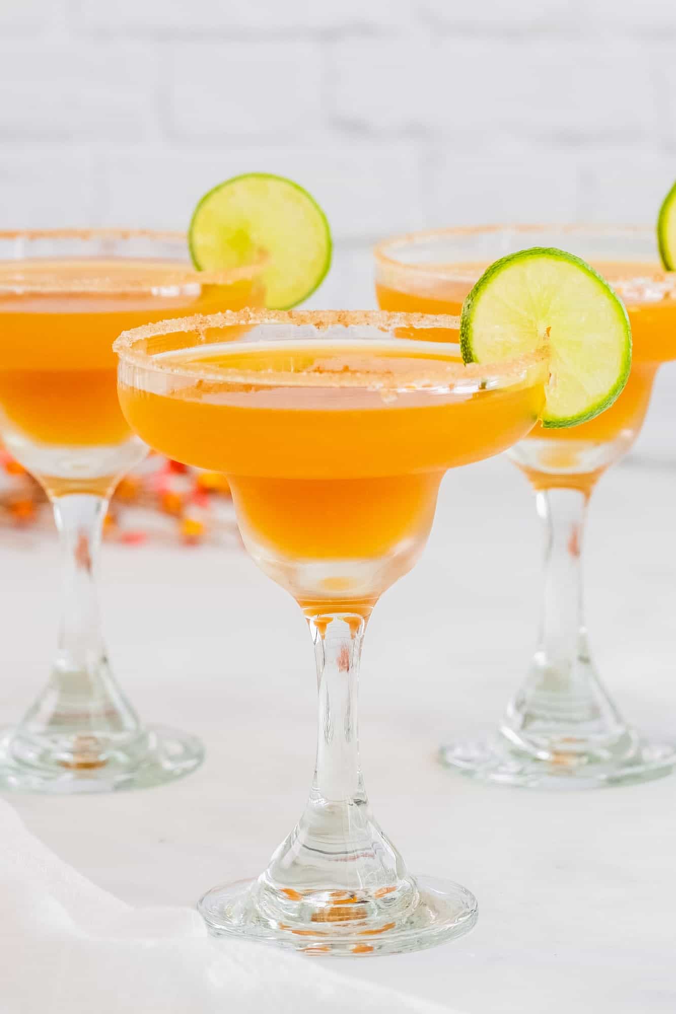 three apple cider margaritas with sugar rims and lime slices.