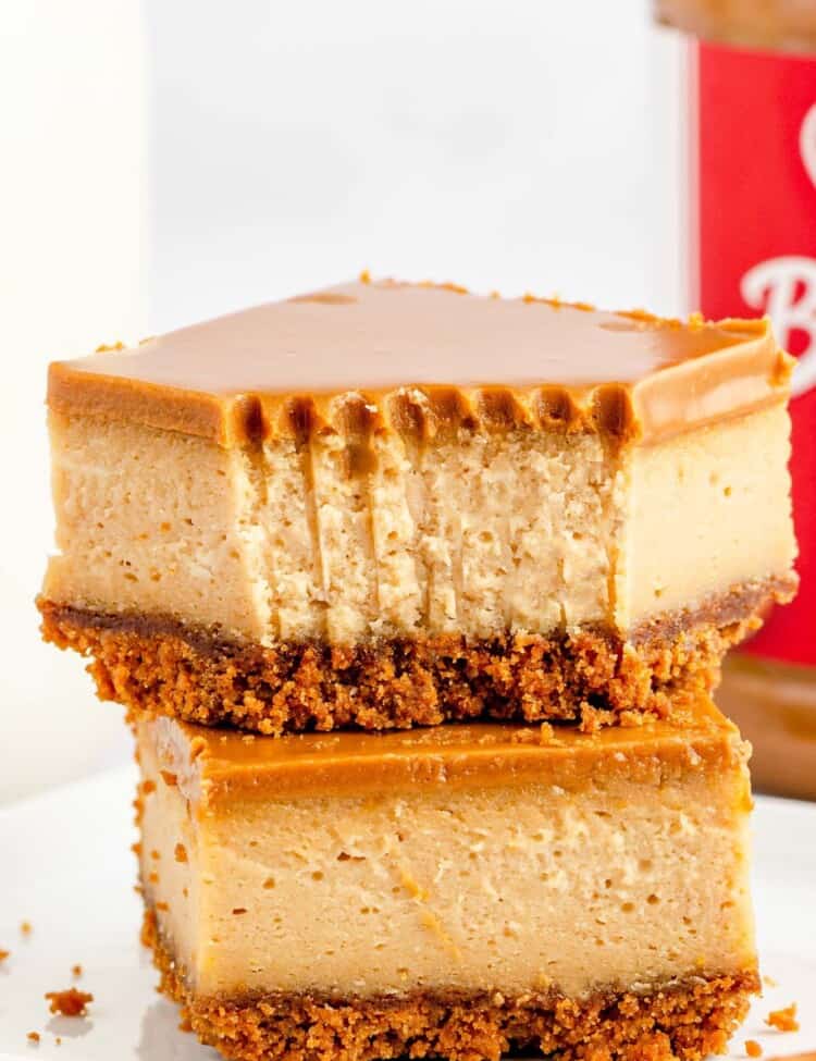 two thick biscoff cheesecake bars stacked on each other. The top has had a bite taken with a fork.