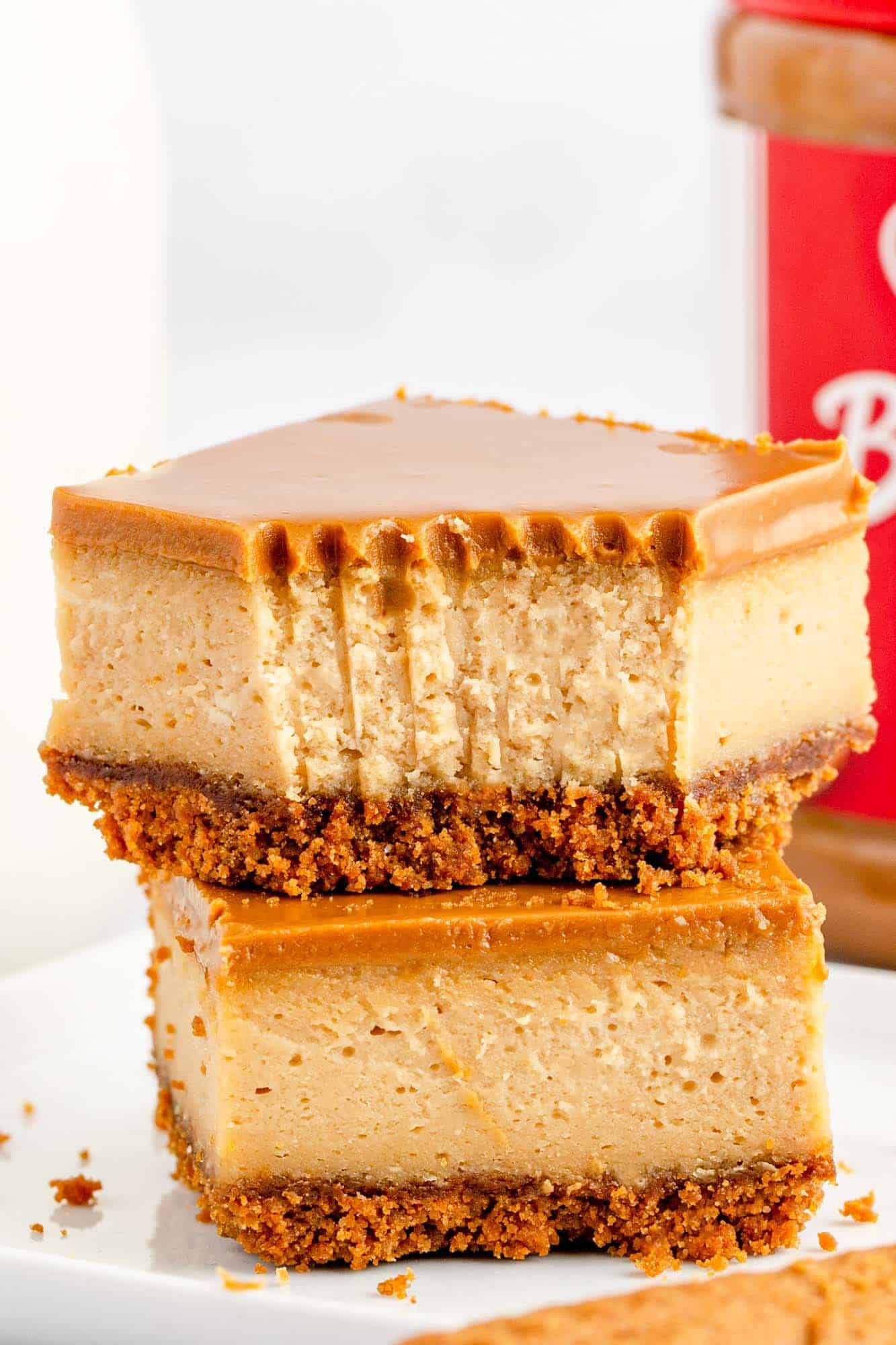 two thick biscoff cheesecake bars stacked on each other. The top has had a bite taken with a fork. 