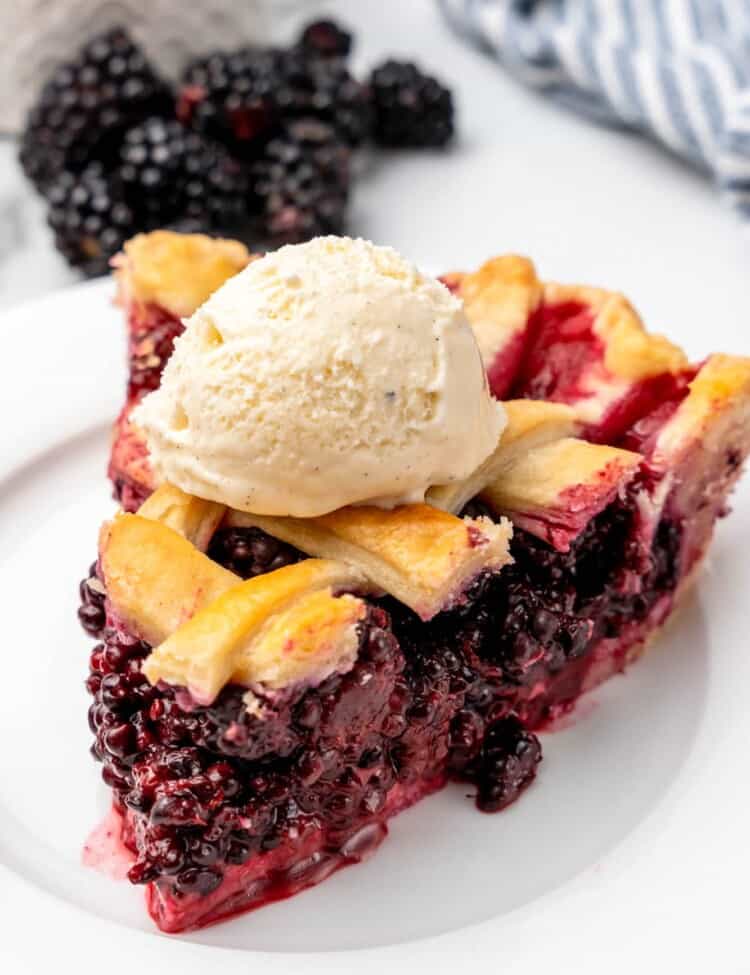 a slice of blackberry pie with lattice top, with a scoop of vanilla ice cream on top